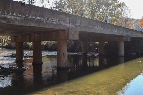 Two people standing on a bridge looking out at a river