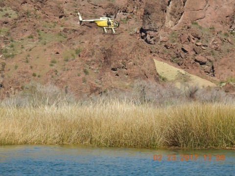 A helicopter flying over a body of water in front of a mountain