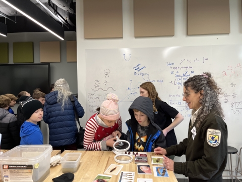 A U.S. Fish and Wildlife Service employee talks to students in a classroom about conservation while they observe species on display
