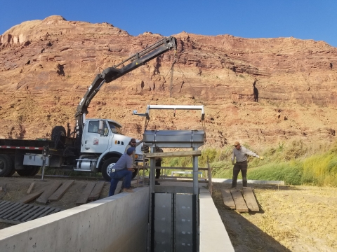 Three individuals constructing a water control structure 