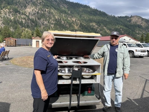 Two people stand by a modified golf cart carrying salmon eggs