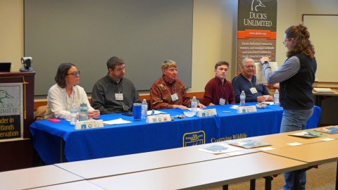 representative shows a junior duck stamp artwork entry to the five judges in Bismark, ND, in March 2025.
