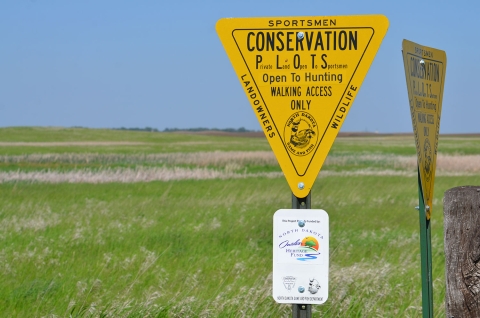 A sign identifying the prairie behind it as part of North Dakota's Outdoor Heritage Fund program Conservation Public Lands Open to Sportsmen (PLOTS) 