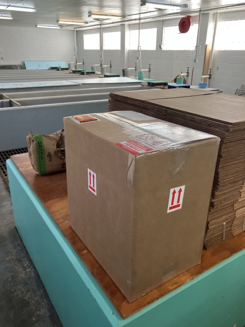 A brown cardboard packing box covered in stickers sits on a table.