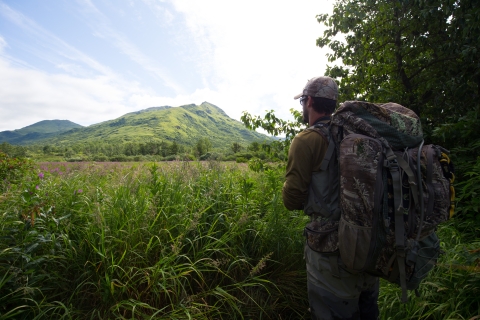 With a full pack of gear for maintaining remote wildlife cameras, volunteer Andy Orlando looks for the best route across a large meadow.