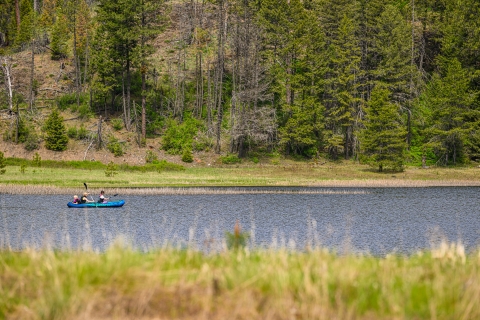 A family uses a small boat to paddle around a pond