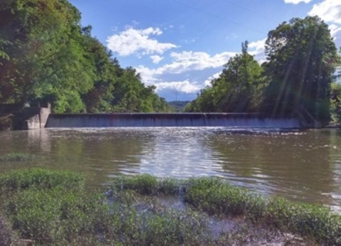 A river in the foreground leading to a dam in the background.