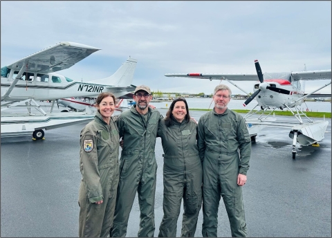 four people standing in front of airplans