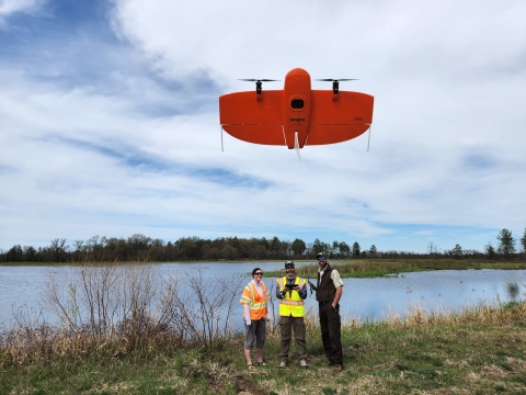 Skydio X10 taking off with three people and w wetland in the background