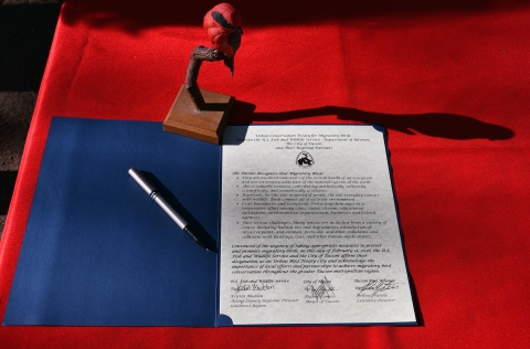 a signed document with signatures and a red bird figurine