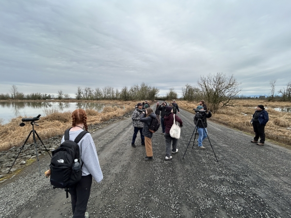 Group of students looking for birds at the marshes through binoculars and spotting scopes