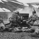 WWII soldiers behind gun with snowy hillside in the distance