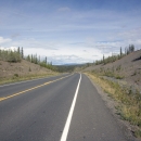 View of a two-lane highway cutting through Alaskan wilderness.