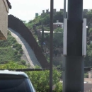A tall wall is shown on a hillside representing the border between the United States and Mexico.