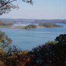 A view of a wide blue river from a forested overlook high above 