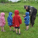 Image of a USFWS staff member showing four children a fishing pole