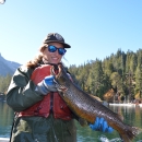 A biologist holds a Lahontan cutthroat trout on top of a small fishing boat with mountains in the background.