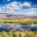 A wetland scene with clouds reflecting in very still water. 