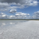 Floor bed covered with salt and water surrounded by semi-covered cloud. 