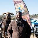 A man in a brown uniform stands in front of a FWS banner