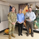Three people stand together, one holding an award plaque