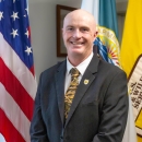 man in suit in front of US, FWS flags