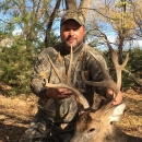 Robbie in camouflage holding the antlers of a deer he hunted. 