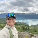 Women standing atop a mountain with a glacial lake in the background.