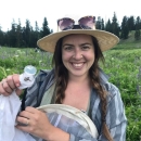  A woman with a wide brimmed hat on holding a net in an alpine meadow