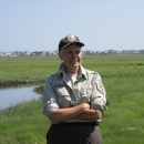 LMRD biologist, Dr. Susan Adamowicz, stands on a salt marsh at Rachel Carson National Wildlife in Wells, Maine. The resort homes of Wells Beach are in the distance.