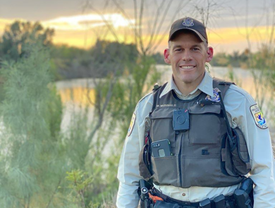 a uniformed officer poses for a picture at the edge of a Southern Texas landscape 