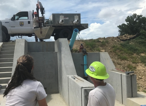 Edenton NFH staff lower bucket with a crane into dry kettle as a test before adding fish to pond.