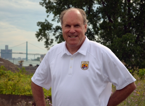 man in white shirt poses with city in the background