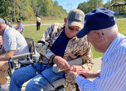 Two elderly men removing a hook from a fish