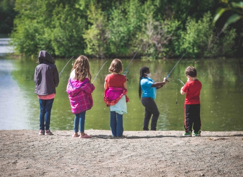 woman in a mask teaching youth how to fish