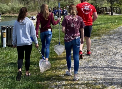 Students with nets walking by a creek