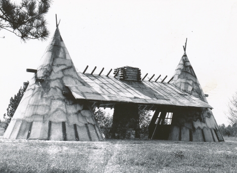 A structure that looks like two teepees connected by a roof with a stone fireplace in between.