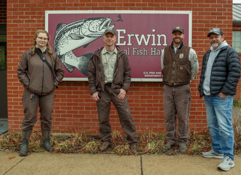 Erwin NFH and TVA staff stand in front of the Erwin National Fish Hatchery sign.