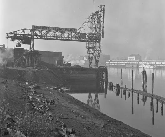 Black and white photo of a Municipal Paving Plant marine industrial crane on the banks of the Willamette River 
