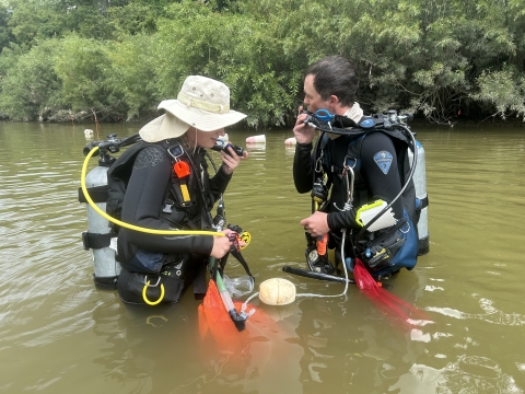 Two biologists in a river with scuba gear.