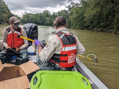 Two USFWS employees on a boat conducting metabarcoding sampling.