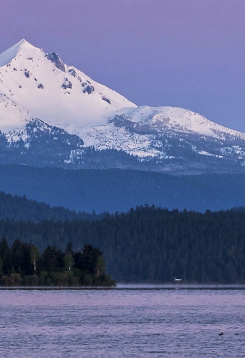 a body of water with a snow covered mountain in the background