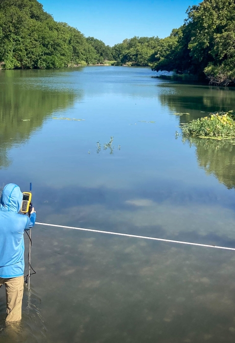 A researcher takes measurements at a mussel research site on the San Saba River