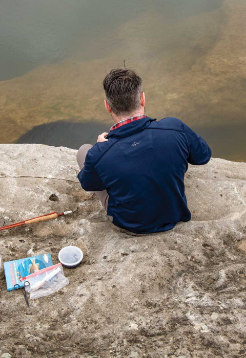 Adam Comer from TPWD sets up microfishing gear on rocky shore. 