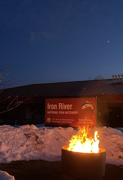 a fire in a fire ring in front of Iron River NFH sign