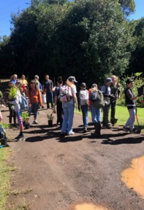 Student and volunteers stand along a dirt road. 