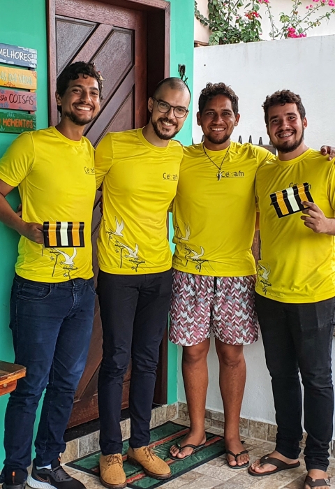 Four people in yellow t-shirts are holding power line markers