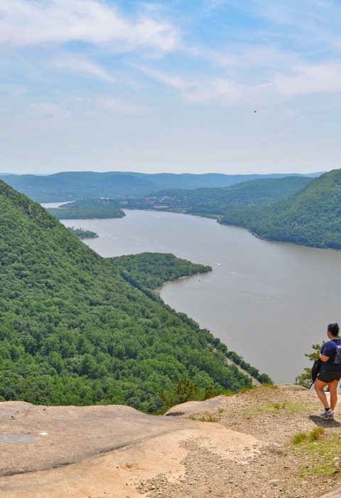 Three people stand on a rocky ledge overlooking a river