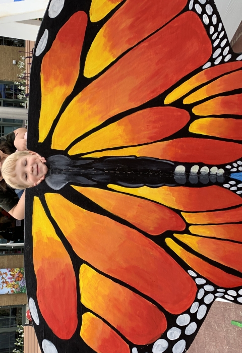 2 small children pose and adult behind a monarch butterfly cutout