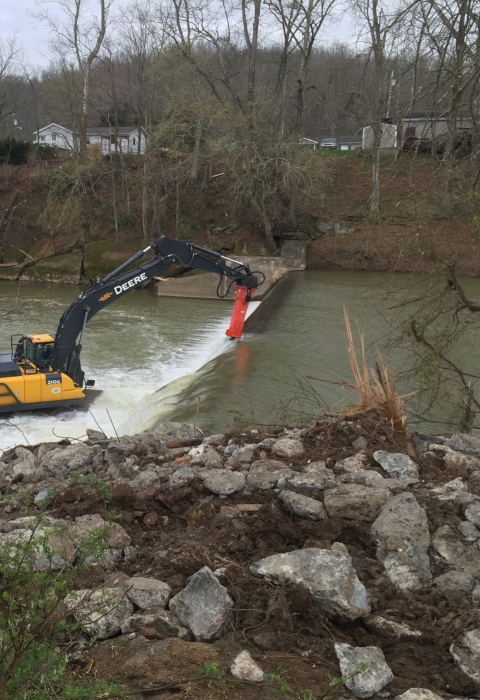 Crane removing dam with danger sign in the foreground